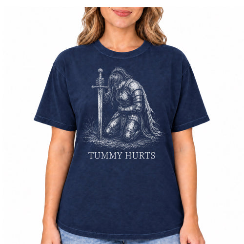 A woman wearing a navy blue short-sleeve t-shirt with a distressed graphic of a kneeling armored knight holding a sword, with the text 'TUMMY HURTS' printed below.