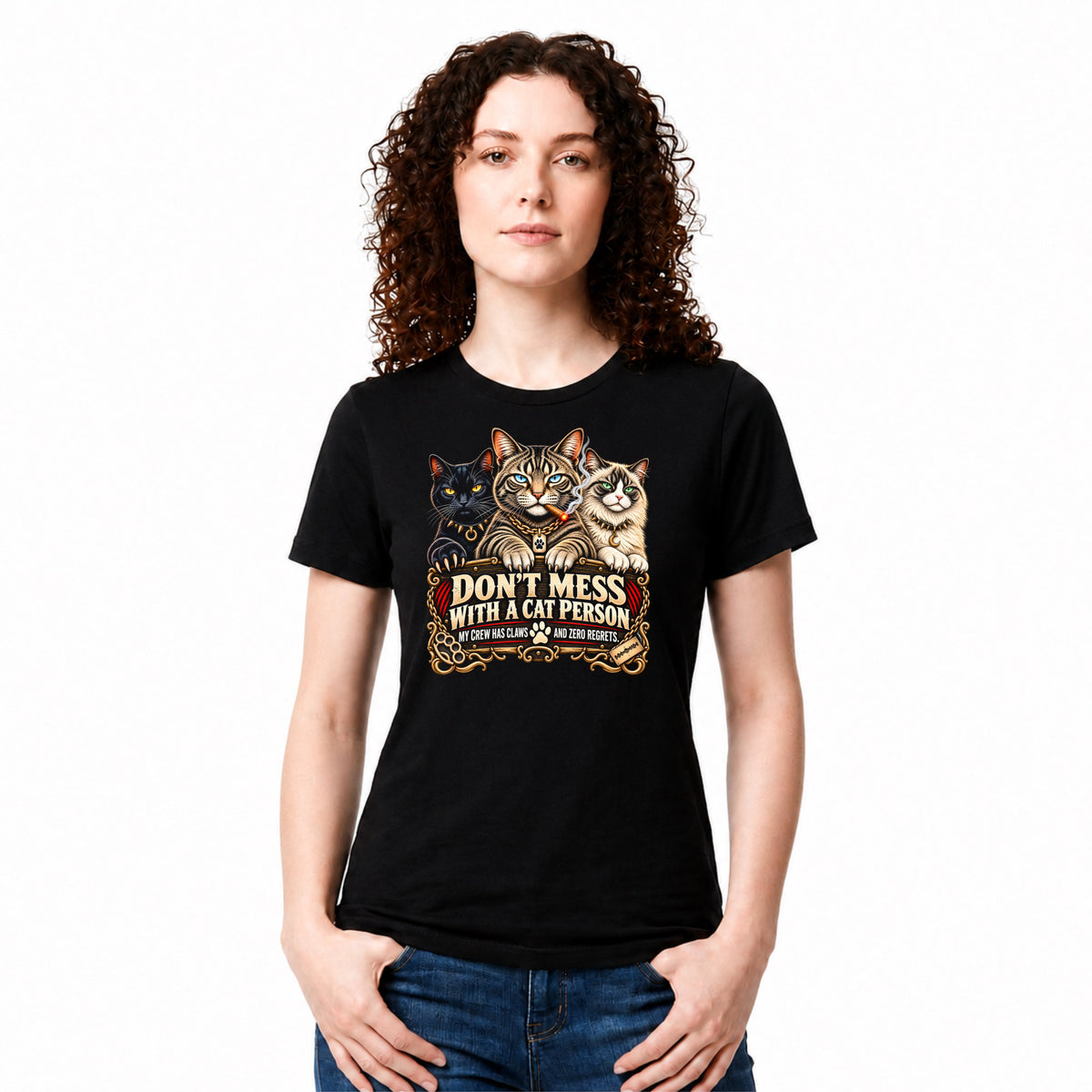 A woman with curly brown hair wearing a black graphic t-shirt with three cats and the text 'DON'T MESS WITH A CAT PERSON' in a vintage western-style design. She is also wearing blue jeans, set against a plain white background.