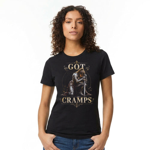 A woman with curly brown hair wearing a black graphic t-shirt that reads 'GOT CRAMPS' with an illustration of a knight in armor, paired with blue jeans, against a plain white background.