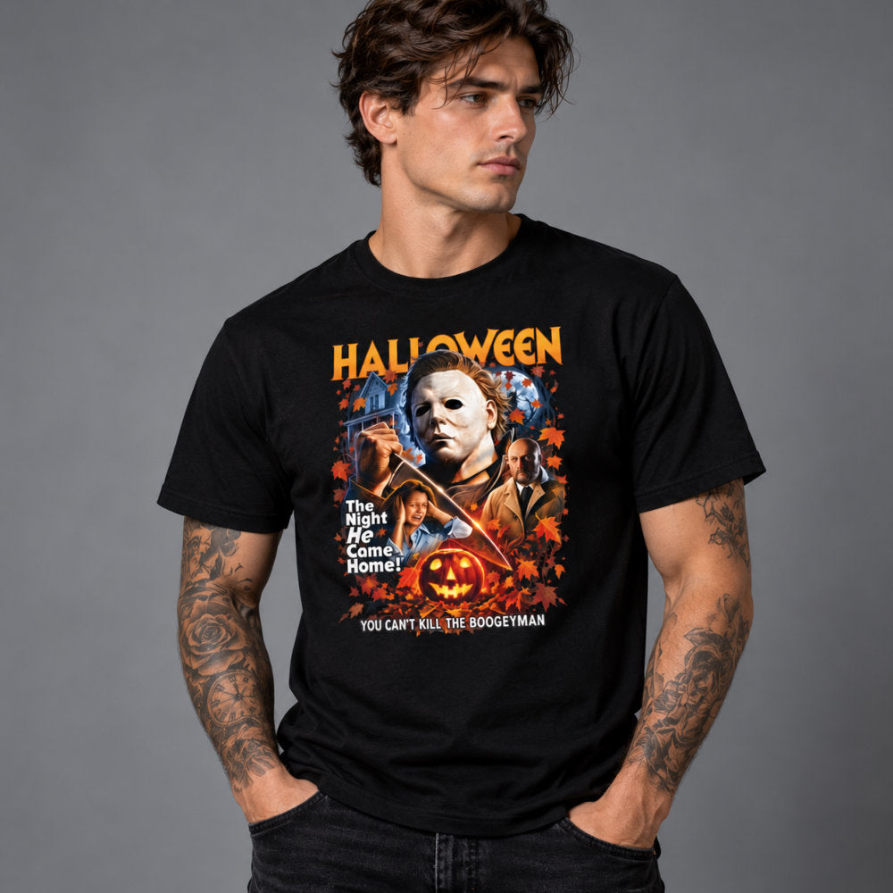 A man wearing a black graphic t-shirt featuring a Halloween-themed print with Michael Myers, a pumpkin, and the text 'HALLOWEEN' and 'YOU CAN'T KILL THE BOODLEYMAN', set against a solid gray studio background.