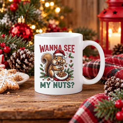 A white ceramic mug with a Christmas-themed squirrel graphic and the text 'WANNA SEE MY NUTS?' sits on a wooden table surrounded by holiday decorations including pine branches, red ornaments, a candle lantern, and a plaid cloth.