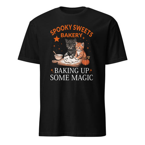 A black short-sleeve crewneck t-shirt featuring a graphic design on the front. The design displays the text 'SPOOKY SWEETS BAKERY' in orange arched lettering above an illustration of two cats (one black, one orange) baking together with a bowl, spoon, and pumpkin, followed by the text 'BAKING UP SOME MAGIC' in white.