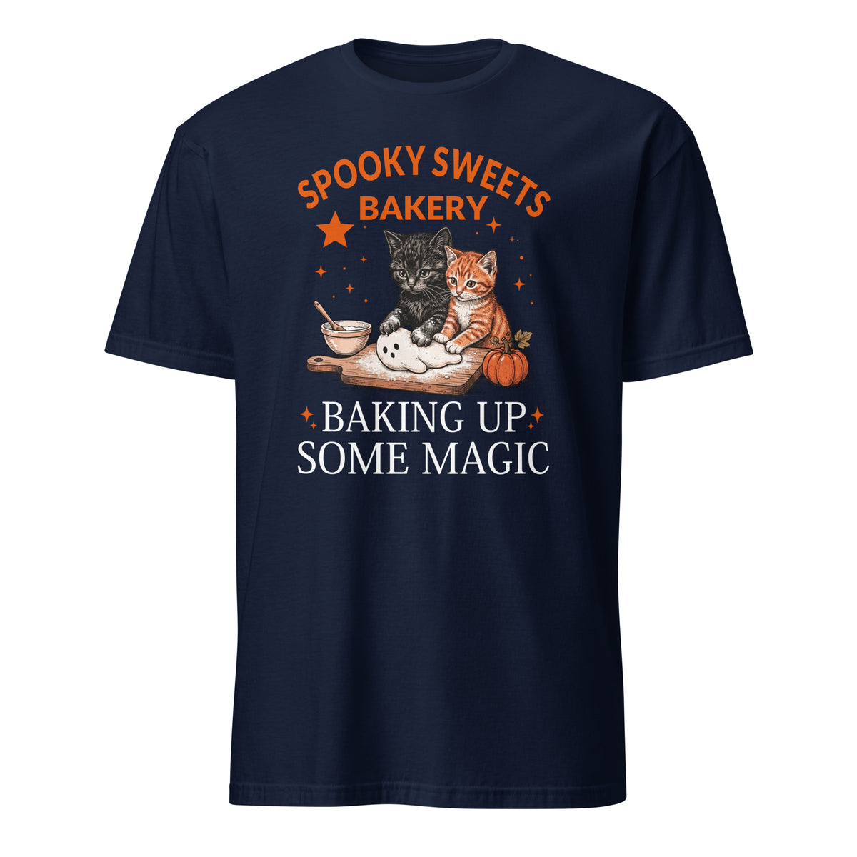 A navy blue short-sleeve t-shirt with a graphic print on the front. The graphic features the text 'SPOOKY SWEETS BAKERY' in orange and 'BAKING UP SOME MAGIC' in white, surrounding an illustration of two cats (one black, one orange) baking with sugar and a pumpkin on a wooden board.