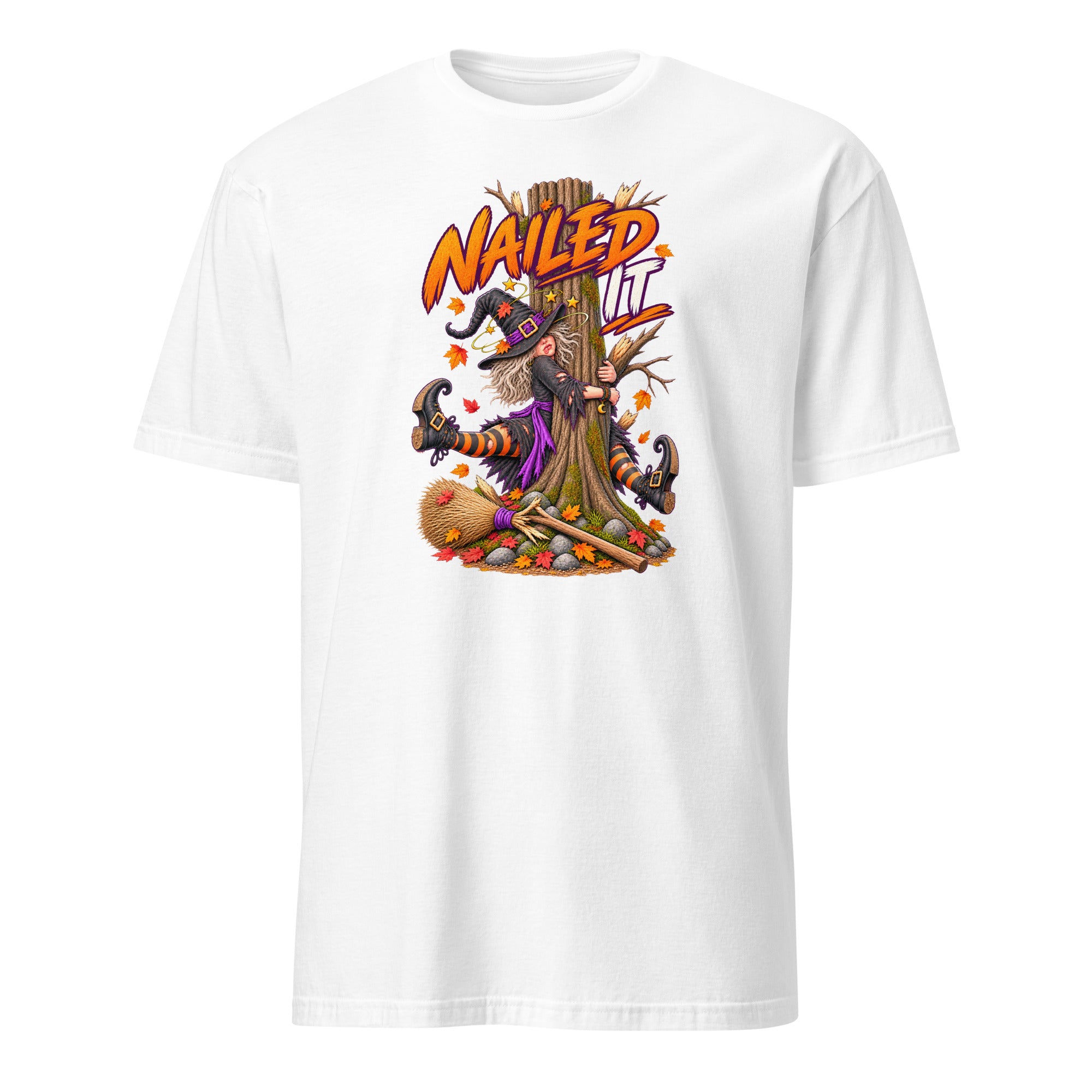 A white short-sleeve crewneck t-shirt featuring a colorful graphic print of a witch with a broomstick nailed to a tree trunk, with the text 'NAIL IT' in orange above.