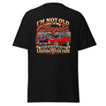 A black short-sleeve t-shirt with a large graphic print on the front. The graphic features a red classic muscle car and stylized text reading 'I'M NOT OLD I'M Classic' and 'LEGENDS NEVER FADE'.