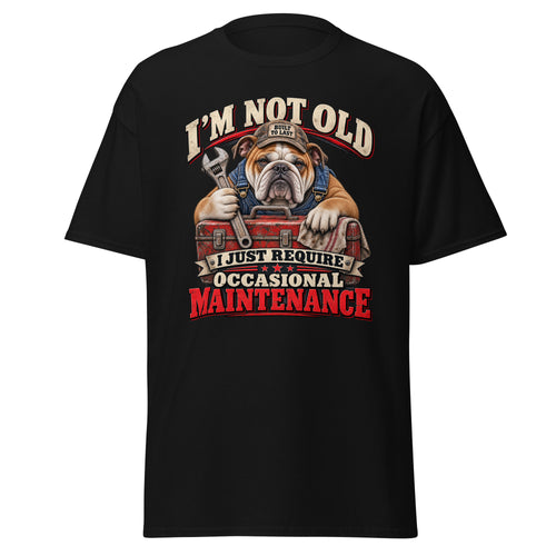 A black short-sleeve crewneck t-shirt featuring a graphic of an bulldog wearing a mechanic's hat and holding a wrench and toolbox, with the text 'I'M NOT OLD I JUST REQUIRE OCCASIONAL MAINTENANCE' in red, white, and beige.