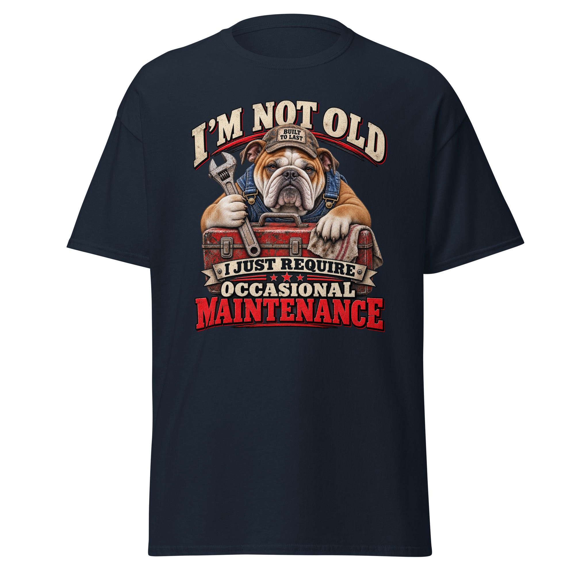 A navy blue short-sleeve t-shirt with a large graphic print on the front. The graphic features an illustration of a bulldog wearing a mechanic's hat and holding a wrench over a red toolbox, surrounded by the text 'I'M NOT OLD I JUST REQUIRE OCCASIONAL MAINTENANCE' in stylized lettering.