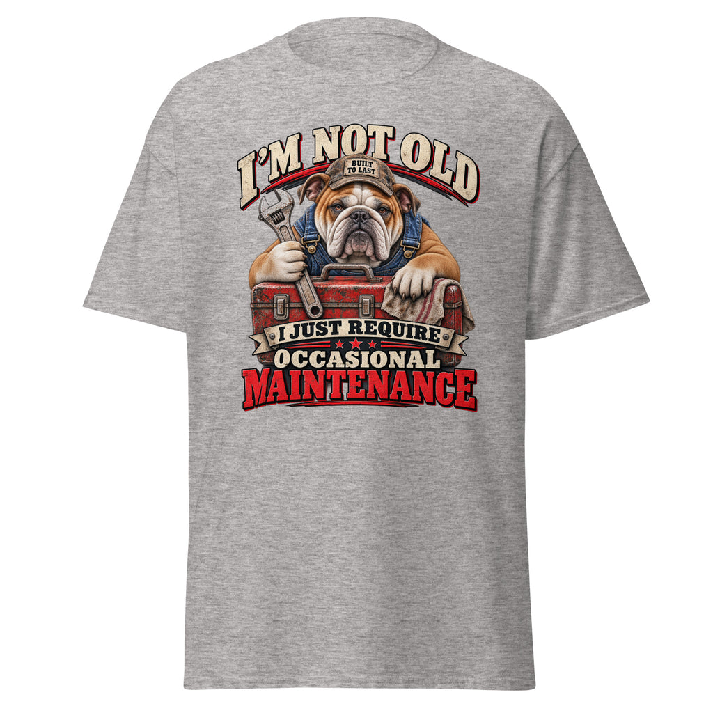 A heather gray short-sleeve t-shirt shown from the back, featuring a large graphic print of an English Bulldog wearing a mechanic's hat and holding a wrench over a red toolbox, with the text 'I'M NOT OLD I JUST REQUIRE OCCASIONAL MAINTENANCE'.