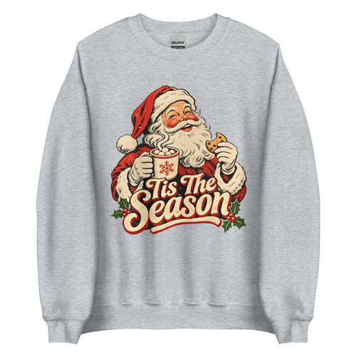 A light heather gray crewneck sweatshirt featuring a vintage-style graphic of Santa Claus holding a mug and cookie with the text 'Tis The Season' in red and cream lettering.
